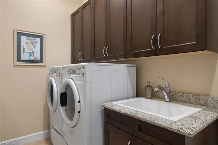 Laundry area featuring cabinets, separate washer and dryer, and sink