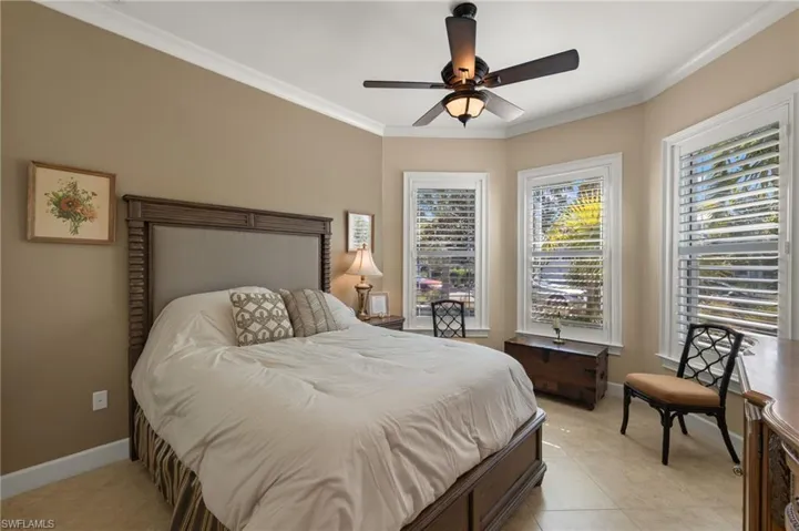 Tiled bedroom with crown molding and ceiling fan