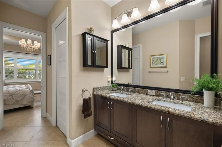 Bathroom featuring a notable chandelier, vanity, and tile patterned floors