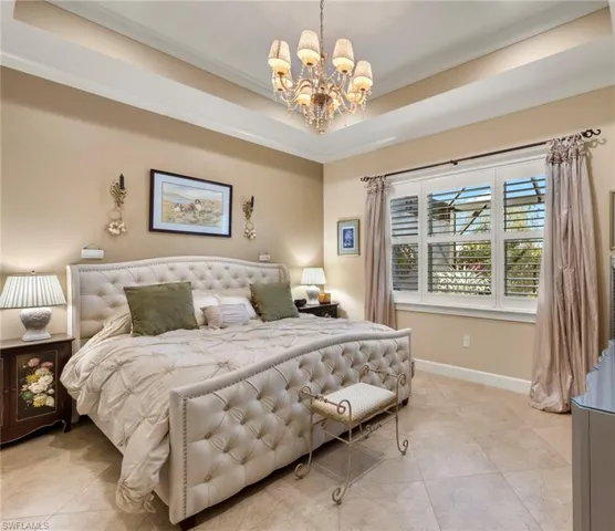 Tiled bedroom featuring a raised ceiling, crown molding, and a chandelier