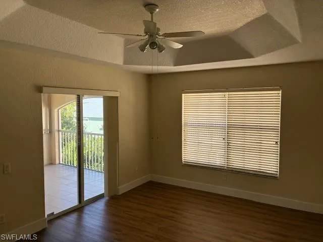 Empty room featuring a textured ceiling, dark wood-style flooring, and ceiling fan
