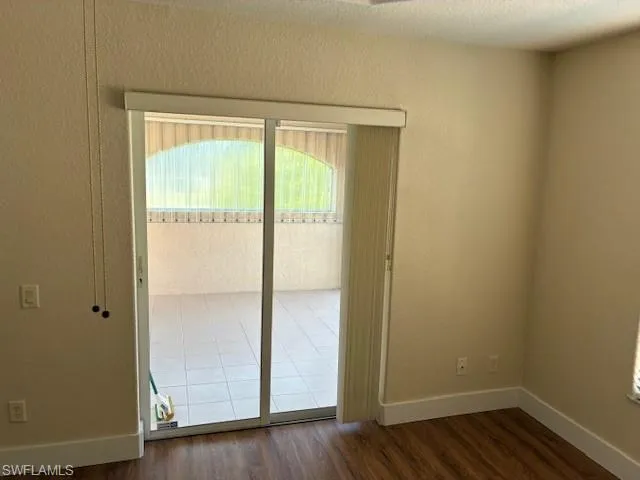 Spare room featuring dark wood-style flooring and a textured wall