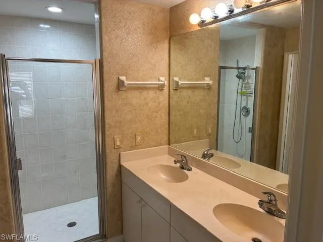 Full bath with double vanity and a shower stall