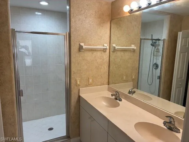 Full bathroom with double vanity and a stall shower