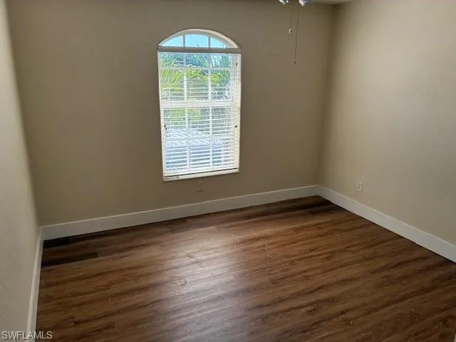 Unfurnished room with dark wood-type flooring and baseboards
