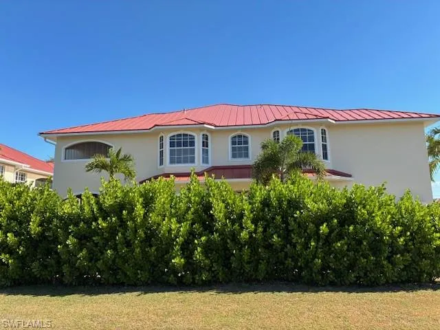 View of front of house featuring stucco siding, a metal roof, and a front lawn