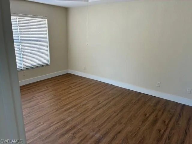 Unfurnished room with baseboards and dark wood finished floors