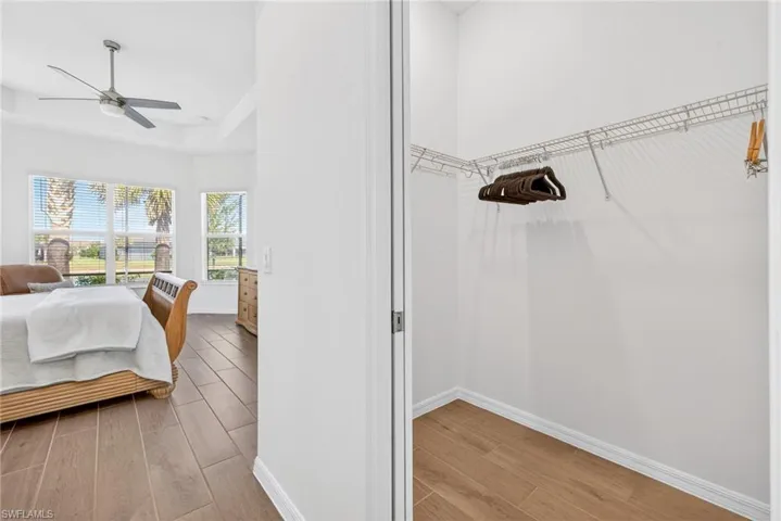 Bedroom featuring wood finish floors, a raised ceiling, and a ceiling fan