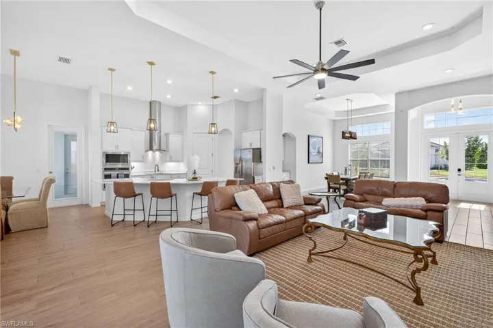 Living room with a chandelier, a tray ceiling, arched walkways, french doors, and a high ceiling