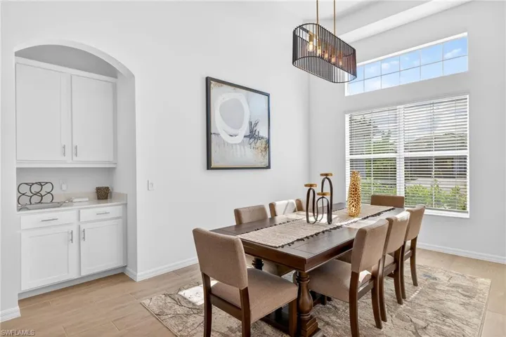 Dining area with light wood-style flooring and a towering ceiling