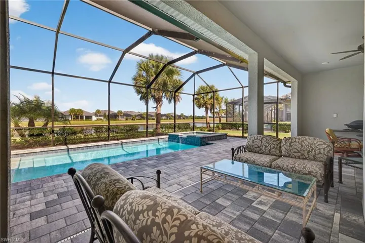 View of swimming pool featuring a sunroom, a patio area, an outdoor living space, glass enclosure, and a residential view