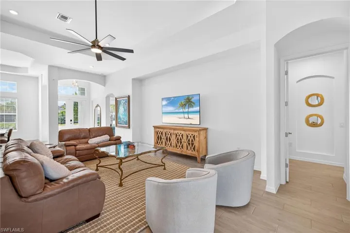 Living room with arched walkways, light wood-style floors, french doors, a ceiling fan, and recessed lighting