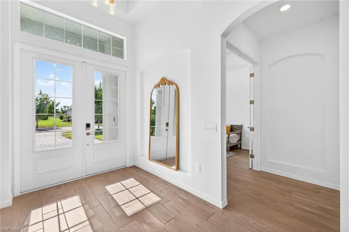 Foyer entrance with wood finished floors, arched walkways, and a towering ceiling