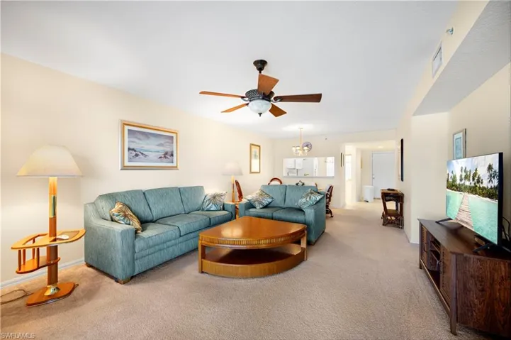 Bedroom featuring a walk in closet, light colored carpet, a ceiling fan, and connected bathroom