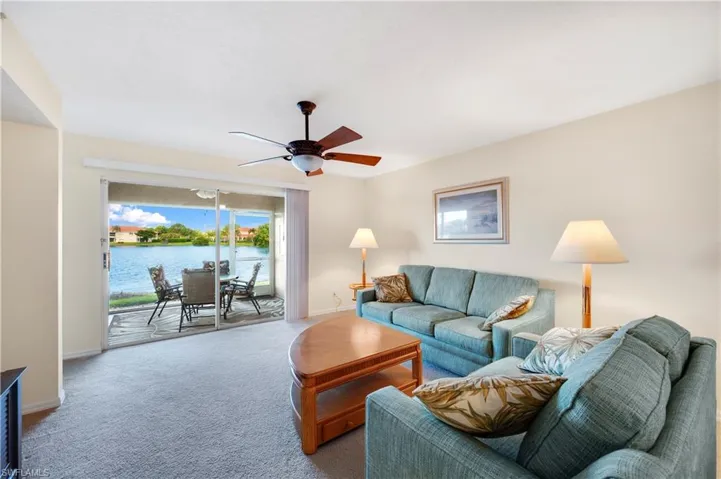 Living area featuring ceiling fan, carpet flooring, and a water view