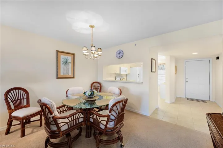 Kitchen with light countertops, white appliances, light tile patterned flooring, white cabinets, and a skylight