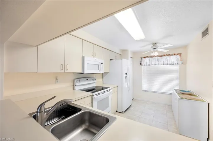 Kitchen featuring white appliances, light countertops, and light tile patterned flooring
