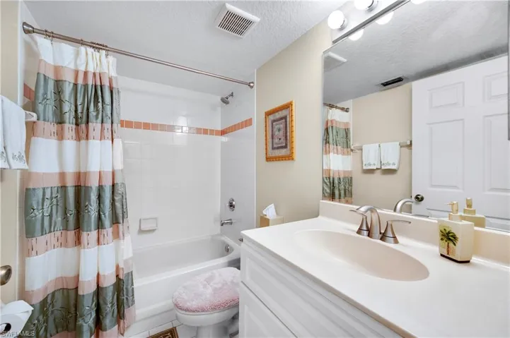 Full bath featuring shower / bath combo, vanity, and a textured ceiling