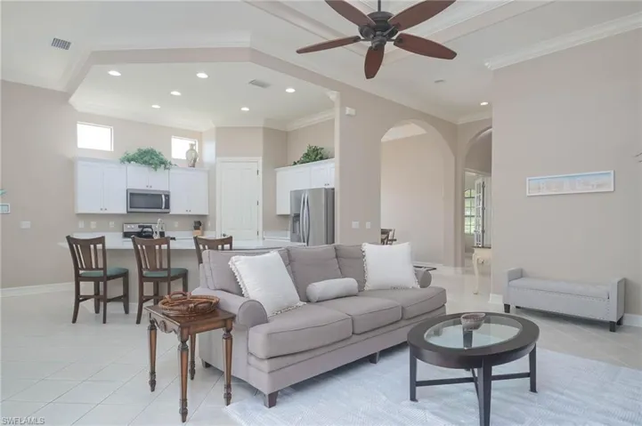 Living room featuring ceiling fan, crown molding, and light tile patterned floors