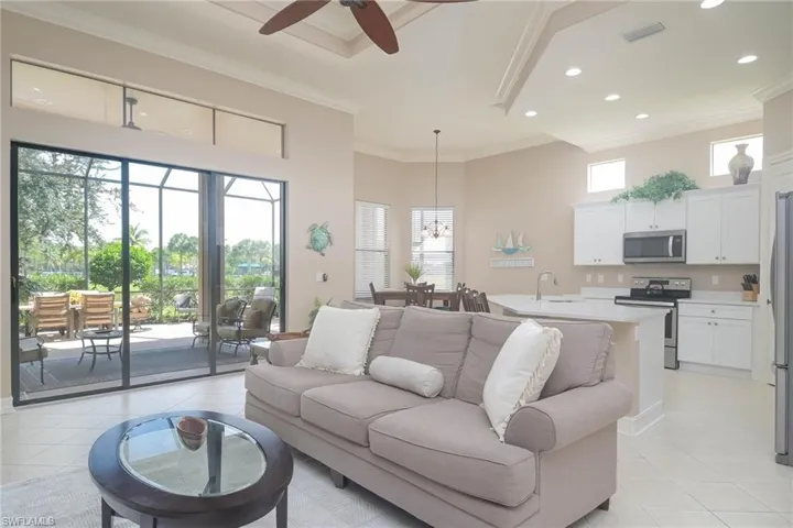 Tiled living room featuring a towering ceiling, ornamental molding, sink, and ceiling fan