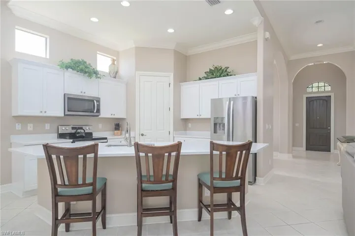 Kitchen featuring a breakfast bar, a kitchen island with sink, stainless steel appliances, and white cabinets