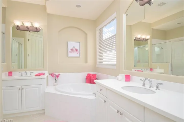 Bathroom featuring plus walk in shower, tile patterned flooring, and vanity