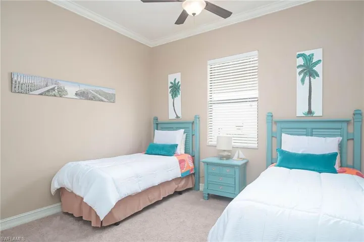Carpeted bedroom featuring ornamental molding and ceiling fan