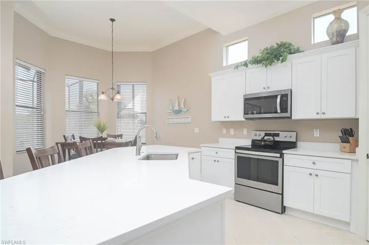 Kitchen with decorative light fixtures, sink, appliances with stainless steel finishes, and white cabinets