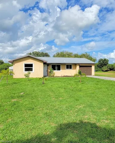 Single story home featuring a garage and a front yard