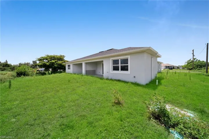 Exterior featuring light gray stucco finish, white trim windows, and a covered patio area with support columns