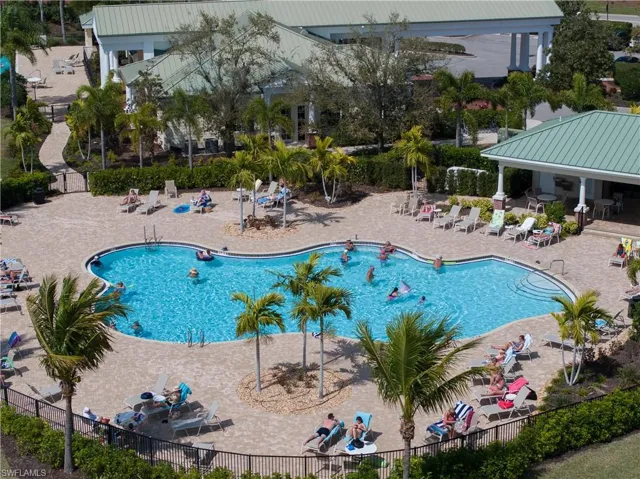 Resort-style swimming pool featuring a curved design, paver decking, and integrated stairs