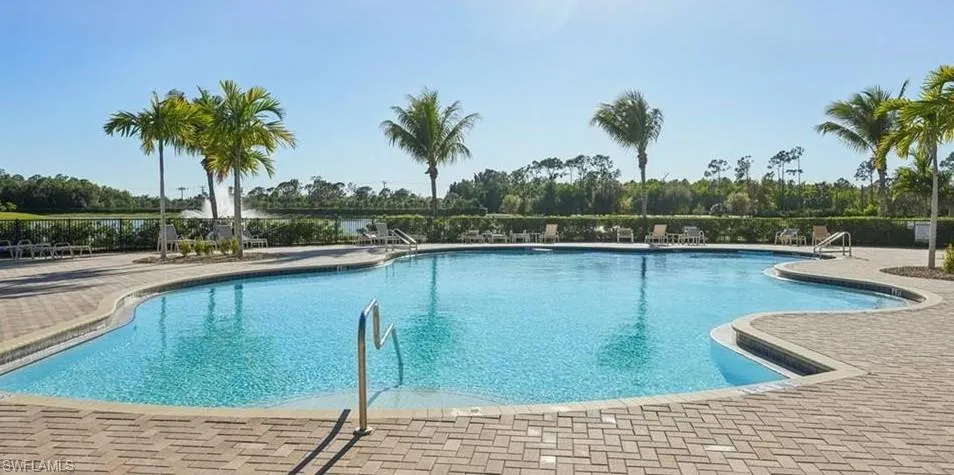 Resort-style swimming pool featuring a curved design, paver decking, and integrated stairs