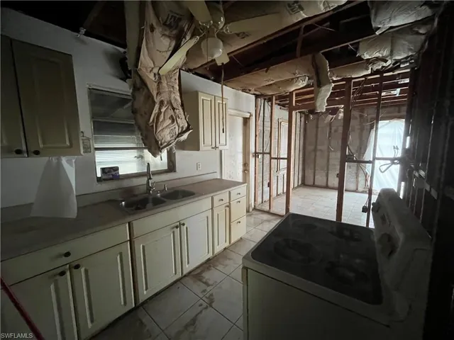 Kitchen featuring ceiling fan, sink, range, and light tile floors