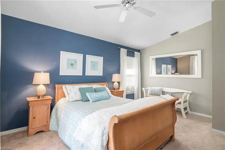 Carpeted bedroom featuring vaulted ceiling and ceiling fan