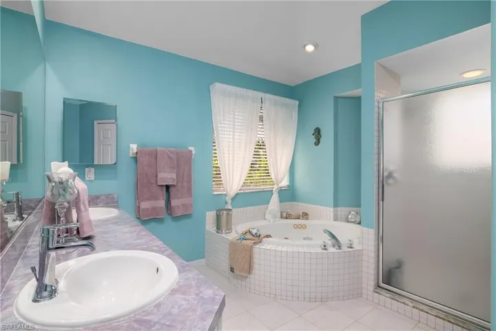 Bathroom with double vanity, separate shower and tub, and tile floors