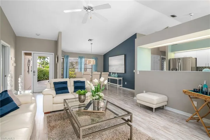 Living room with ceiling fan, vaulted ceiling, and light wood-type flooring
