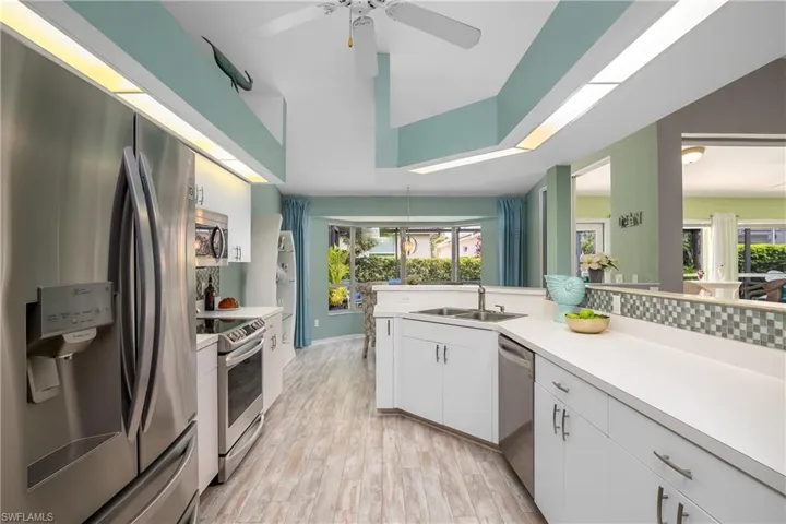 Kitchen with plenty of natural light, stainless steel appliances, light hardwood / wood-style floors, and white cabinets
