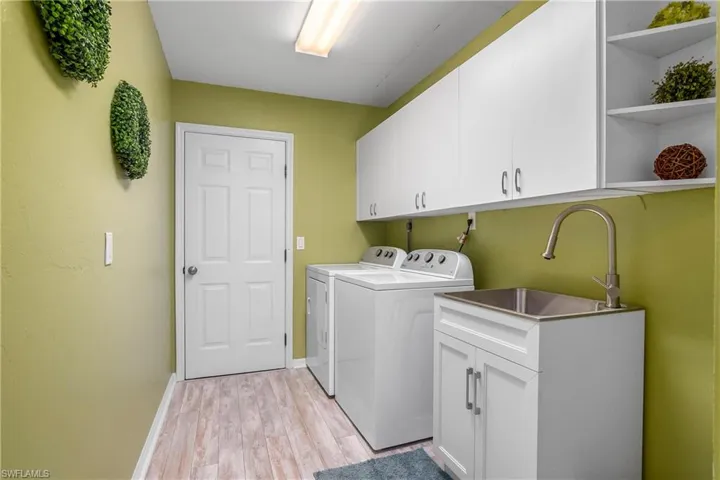 Washroom featuring washer and dryer, cabinets, sink, and light hardwood / wood-style flooring