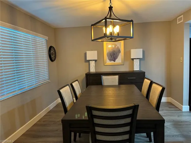 Dining space with dark hardwood / wood-style flooring and an inviting chandelier