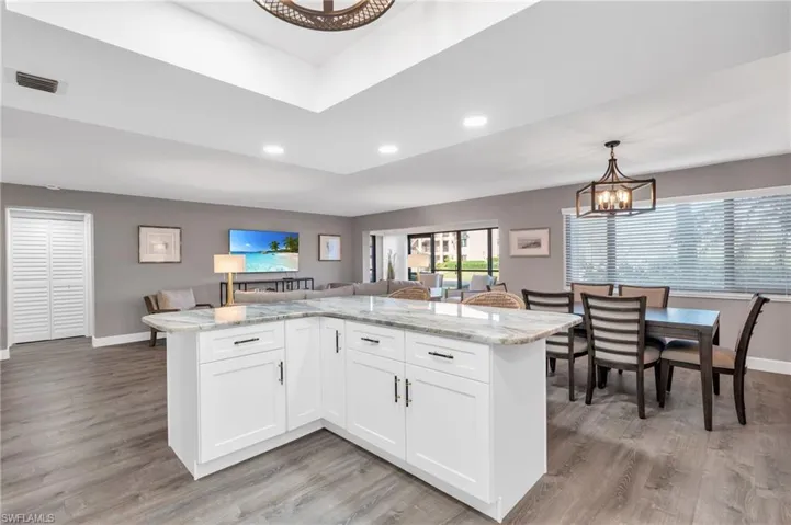 Kitchen featuring light hardwood / wood-style flooring, light stone countertops, decorative light fixtures, and white cabinets