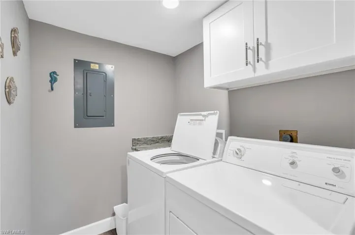 Laundry room featuring electric panel, cabinets, and washer and clothes dryer