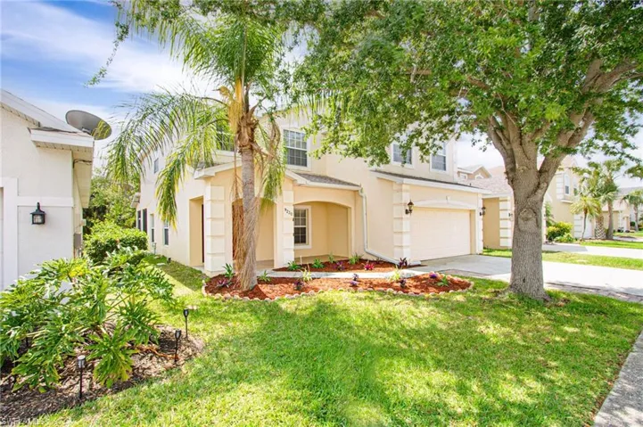 View of front facade featuring stucco siding, concrete driveway, a front lawn, and a garage