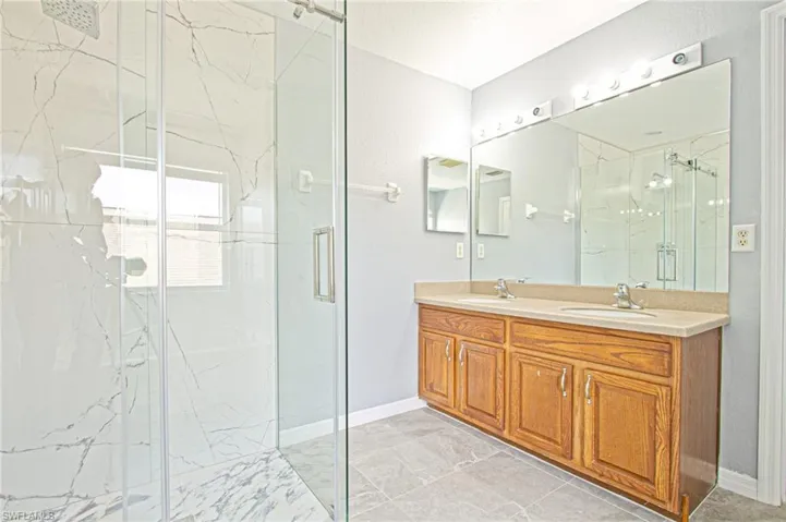 Bathroom featuring a marble finish shower and double vanity