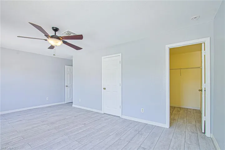 Unfurnished bedroom featuring a spacious closet, light wood-style flooring, and ceiling fan