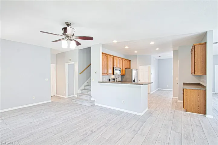 Kitchen featuring recessed lighting, stainless steel appliances, light wood-style flooring, open floor plan, and brown cabinetry