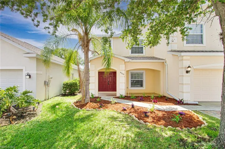 Traditional-style home with stucco siding, a front yard, a garage, and driveway