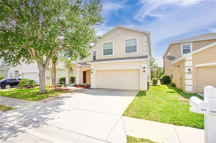 Traditional-style house with stucco siding, driveway, a front lawn, and an attached garage