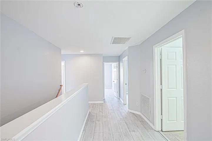 Hallway featuring an upstairs landing, light wood finished floors, and recessed lighting