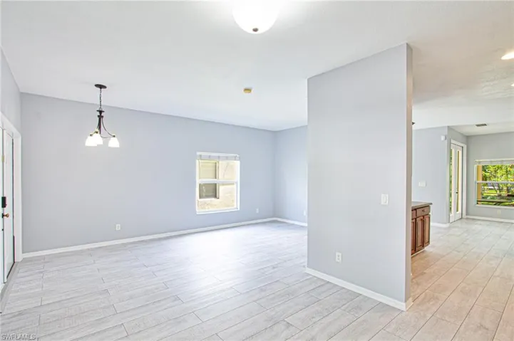 Empty room with a chandelier and light wood-type flooring