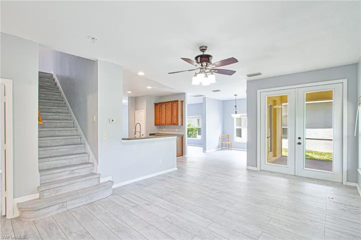 Unfurnished living room featuring french doors, light wood-type flooring, stairs, ceiling fan, and recessed lighting